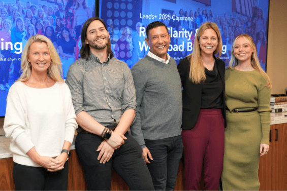 Group of people smiling in front of a PowerPoint presentation.
