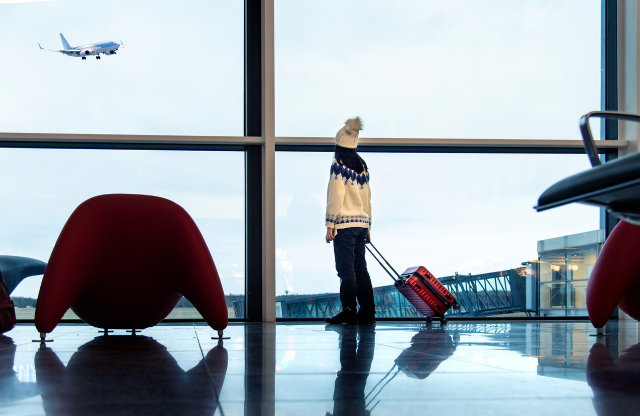 Girl waiting at the airport with suitcase as she prepares for winter travel