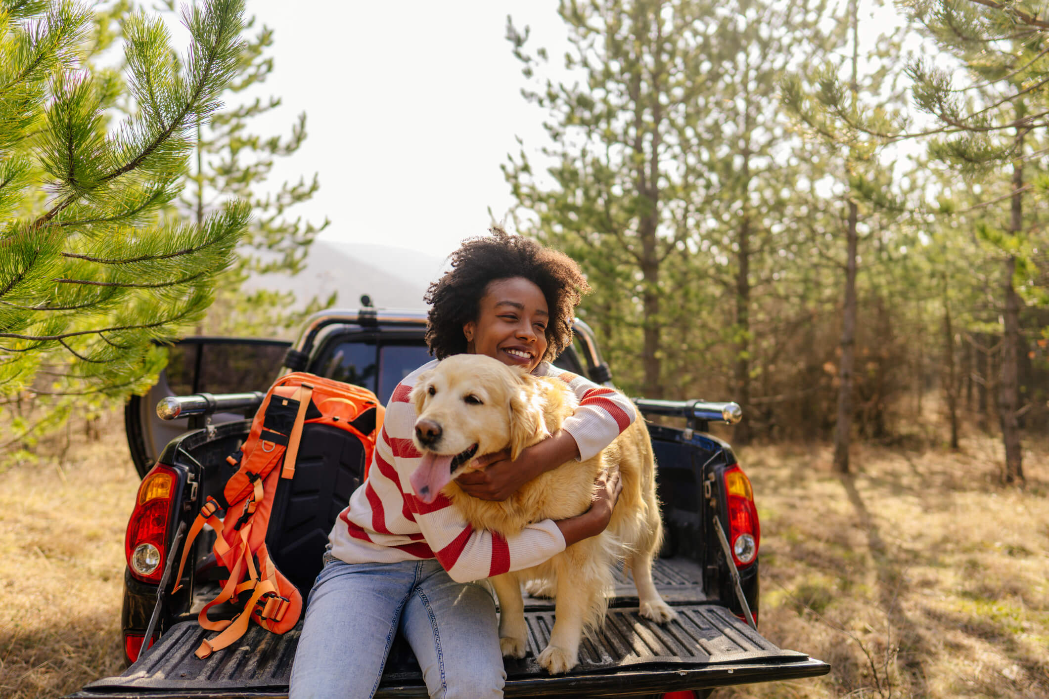Woman hugging dog in back of truck bed