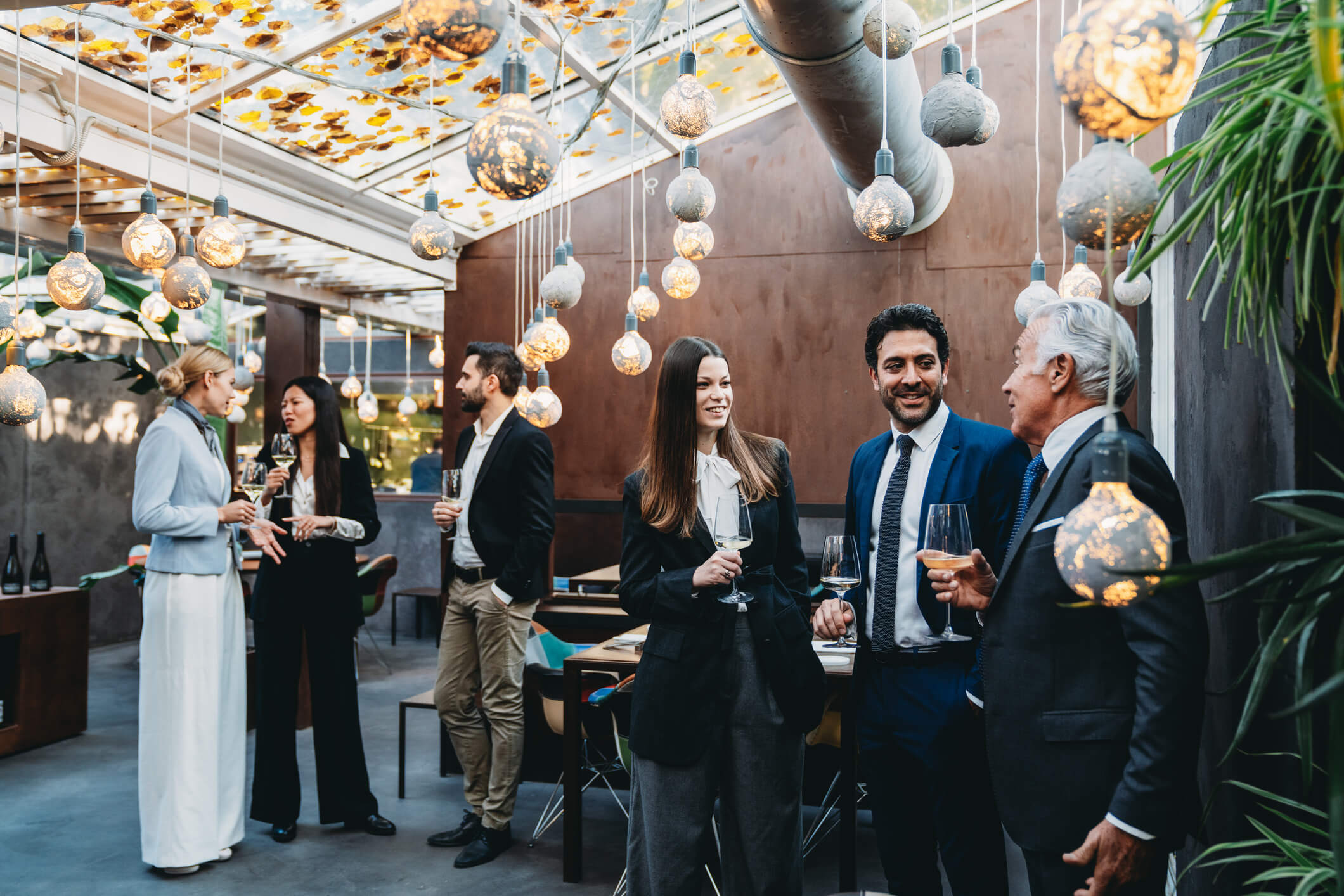 Business people standing in a room with a skylight and modern chanedliers