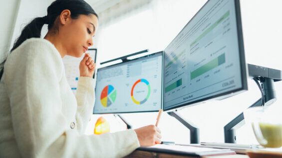 Woman looking at digital analytics on two monitors