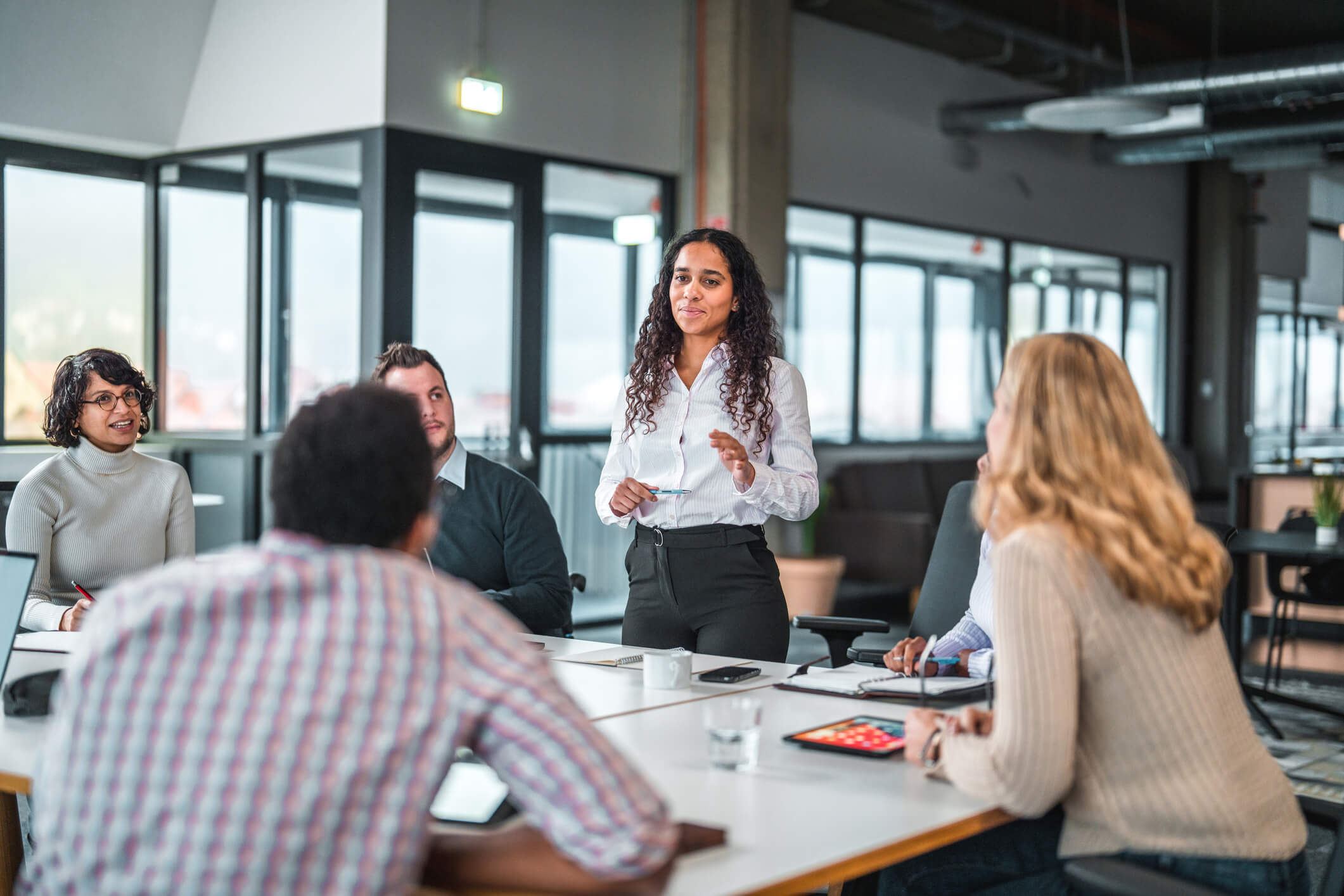 Woman standing at a conference table of people discussing B2B marketing strategies
