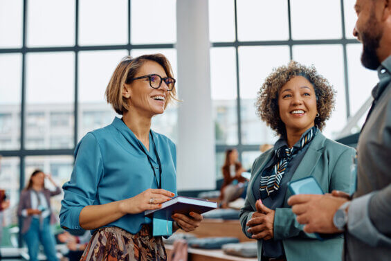 Happy travel advisors talking on a break during an education event in convention center.