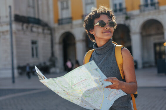 Young woman consulting a map while enjoying her summer trip in lisbon, portugal, discovering the city's charming streets and architecture