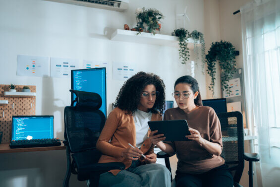 Two women looking at a tablet and discussing the transition from SEO to GEO.