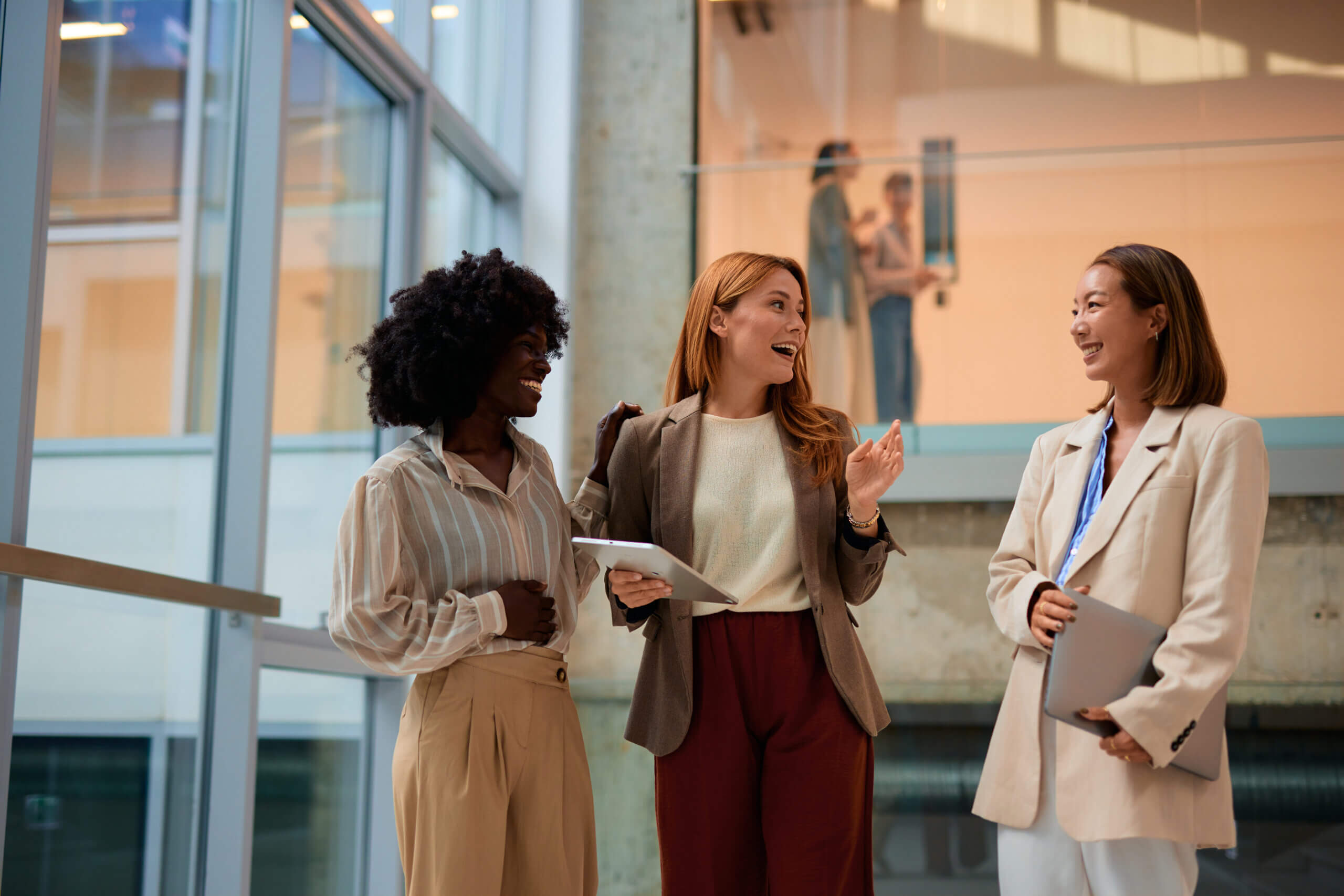 Three business women talking with iPads in a hallway