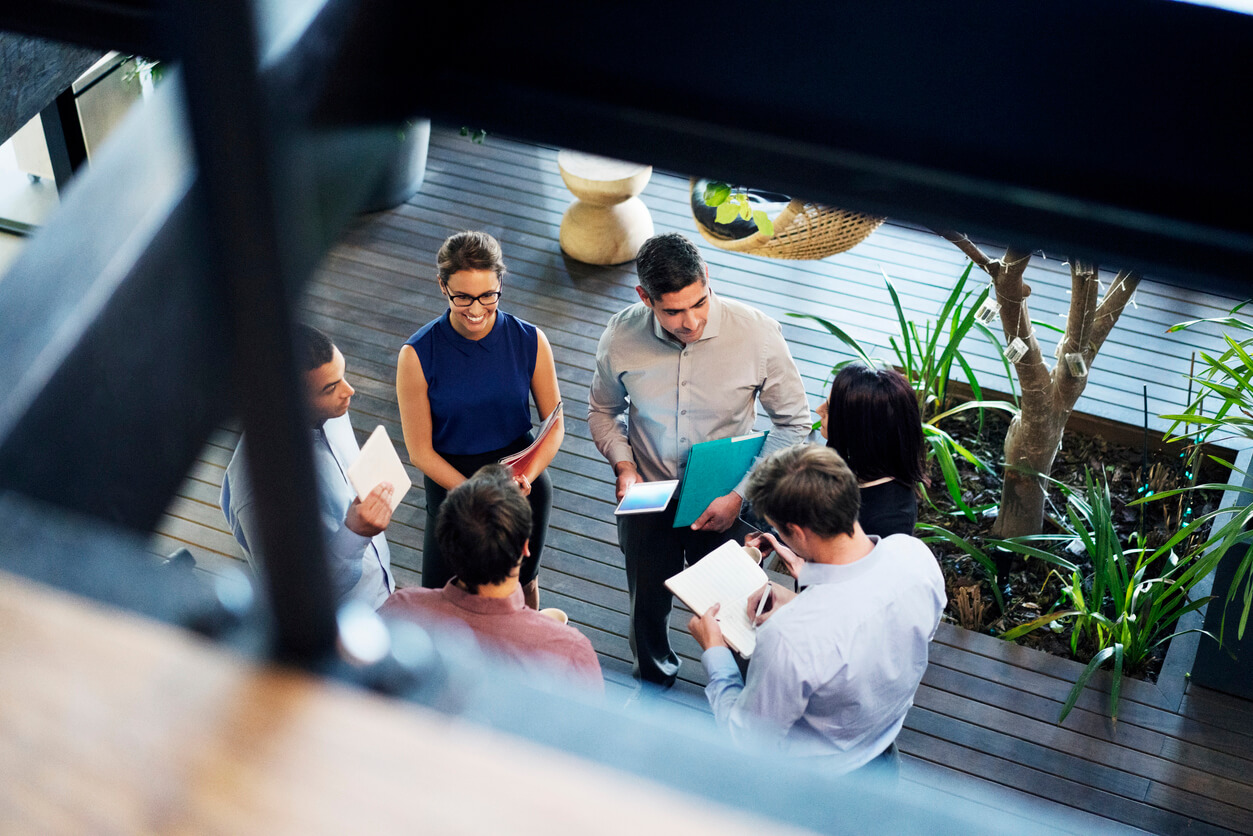 High angle view of meeting planners discussing Winning Strategies in Destination Marketing in the lobby. Male and female professionals are working in office. Focus is on executives at workplace.